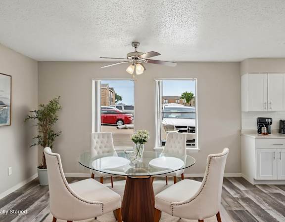 A dining room with a glass table and white chairs.