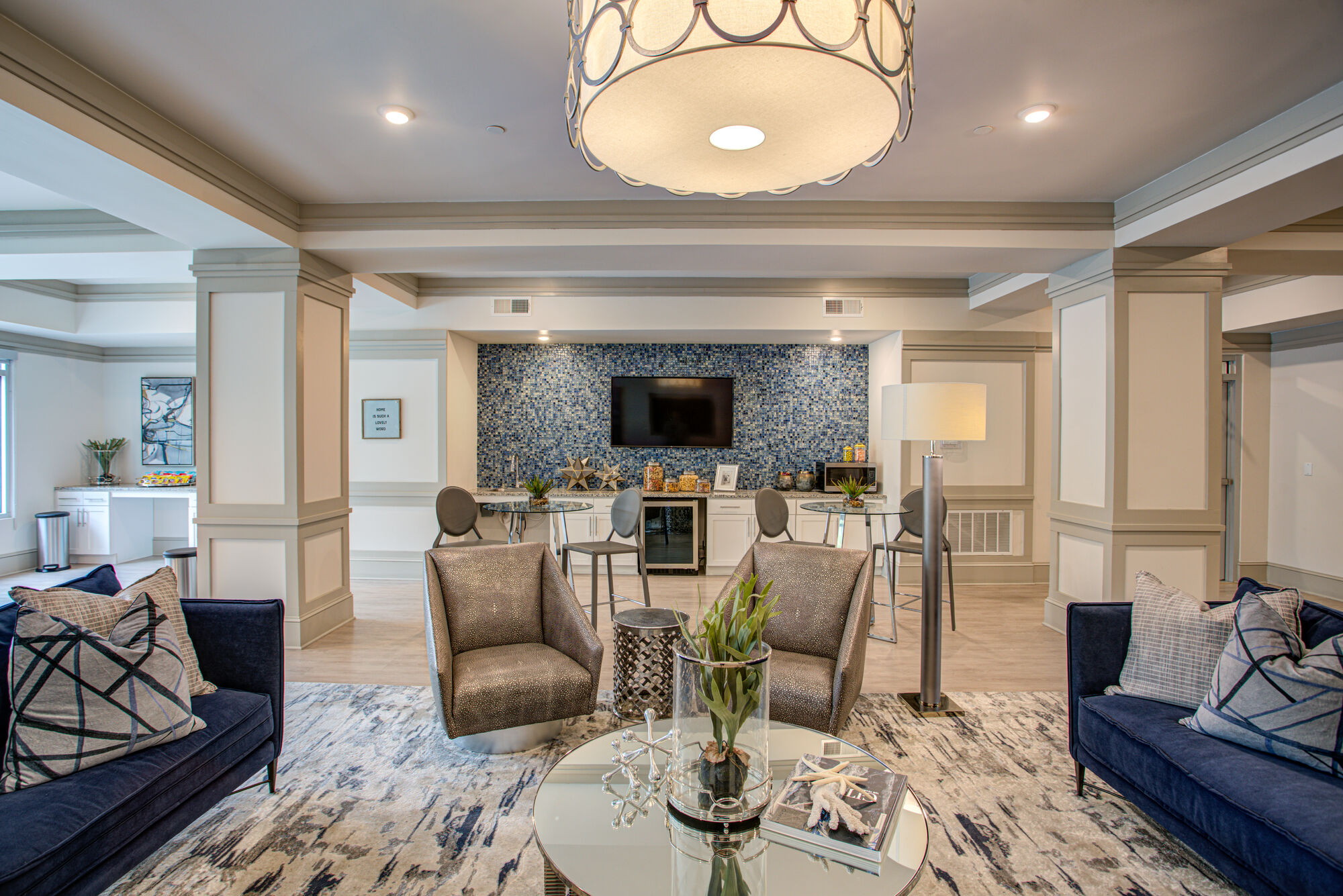 Clubhouse lounge with sofas and arm chairs, kitchenette, and TV