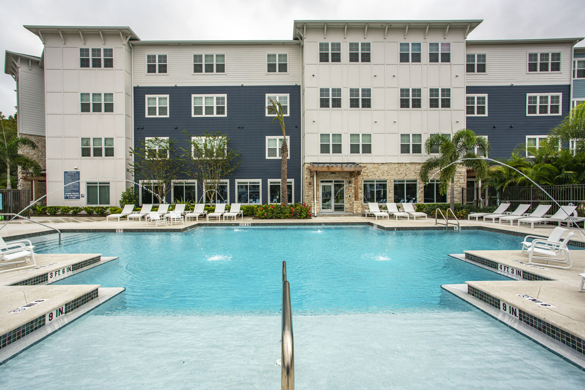 Large swimming pool with deck furniture and palm trees