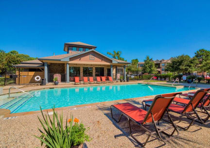 A swimming pool at Lake forest surrounded by beach umbrellas and beach chairs and trees