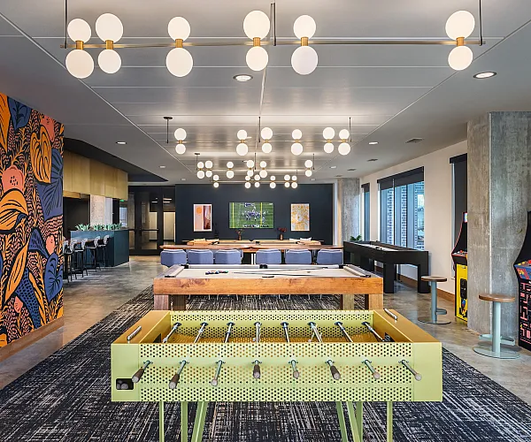 Chic recreational lounge featuring a vibrant foosball table, eye-catching wall art, modern lighting, and arcade games.