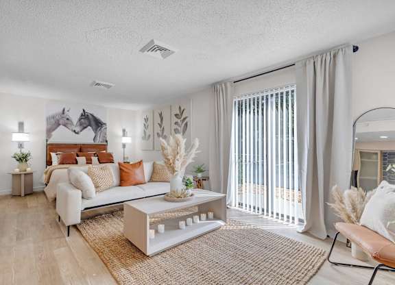 a living room with a couch and a sliding glass door to a bedroom at AVIA Lofts on Liberty Ridge Apartments, Jacksonville