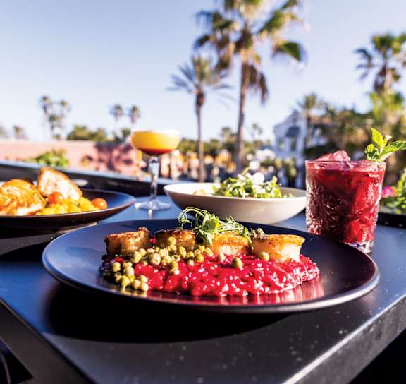 A table with food and drinks on it with a view of palm trees in the background at AVIA Lofts on Liberty Ridge Apartments, Jacksonville 32256