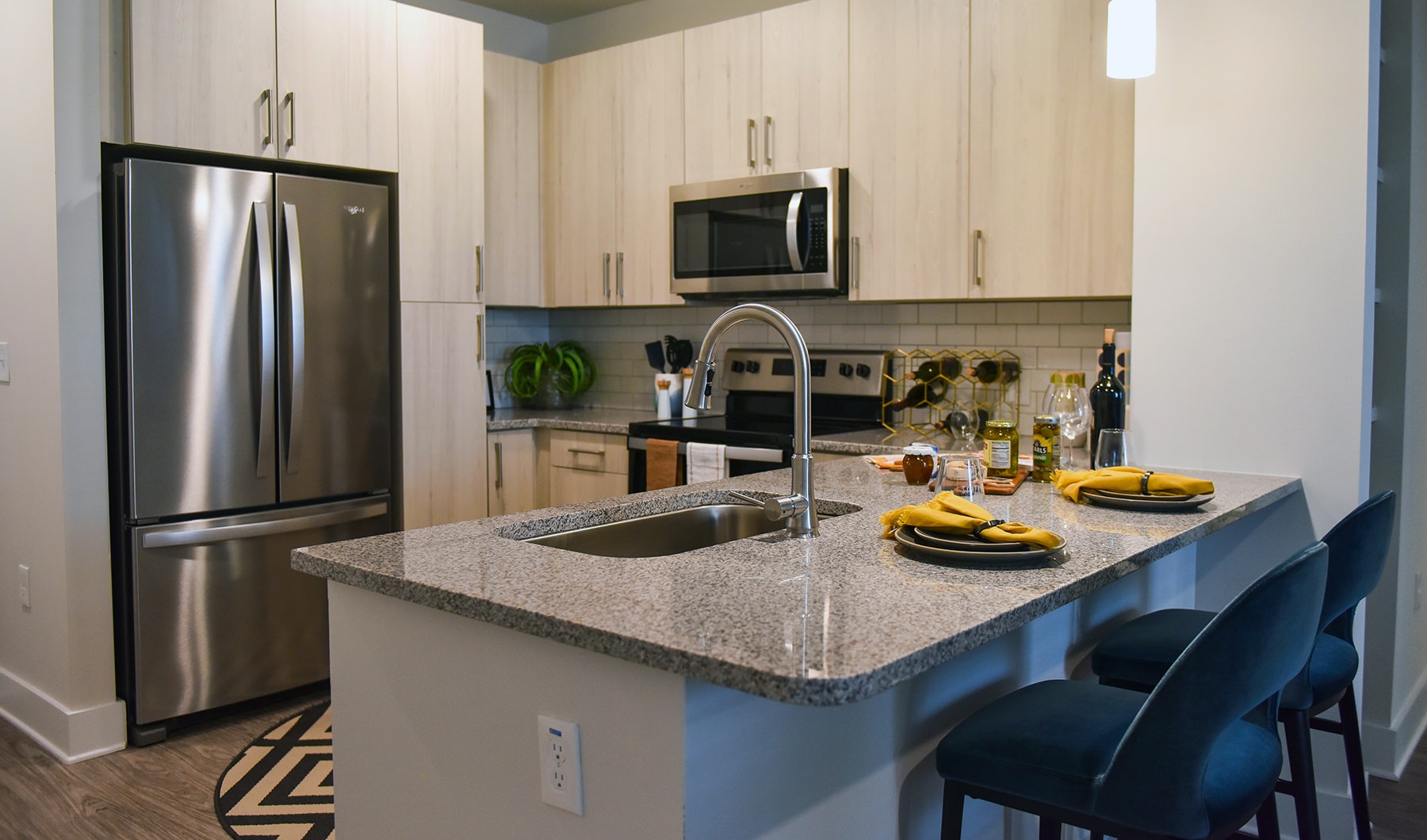 Spacious and well lit kitchen with wood floors and stainless steel appliances.