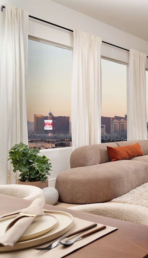 A modern living room with a view of the city skyline at sunset.