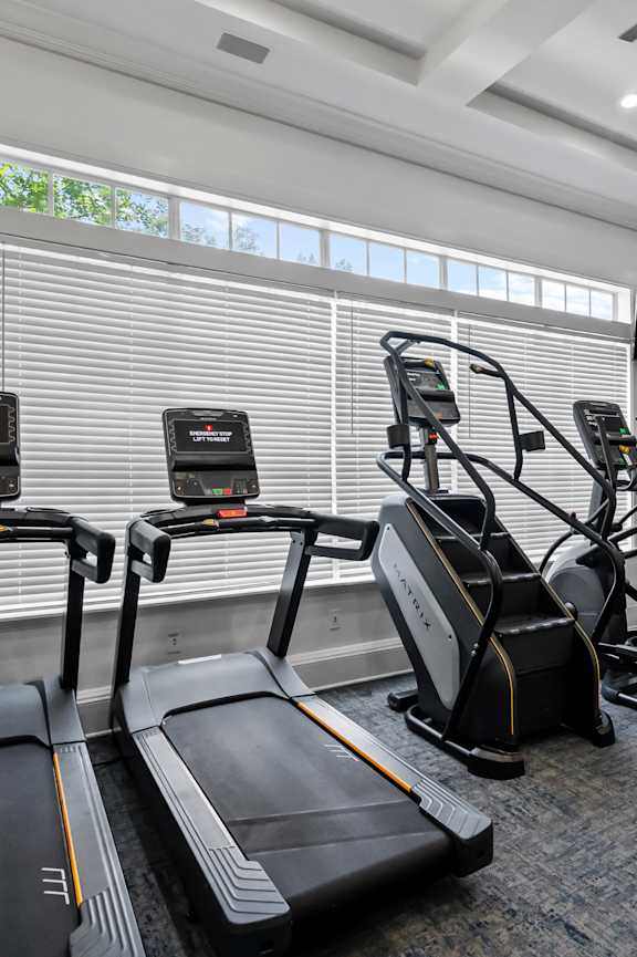 a workout room with treadmills and a tv