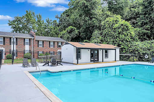 A swimming pool in a backyard with a small house and a fence.