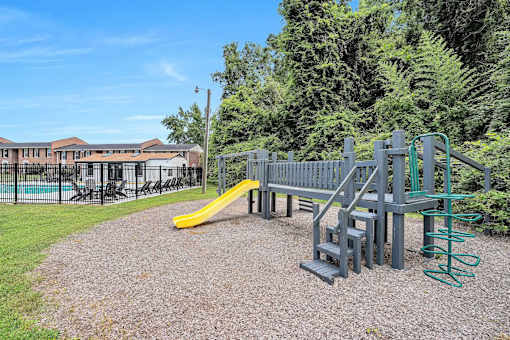 A playground with a yellow slide and a green spring rider.
