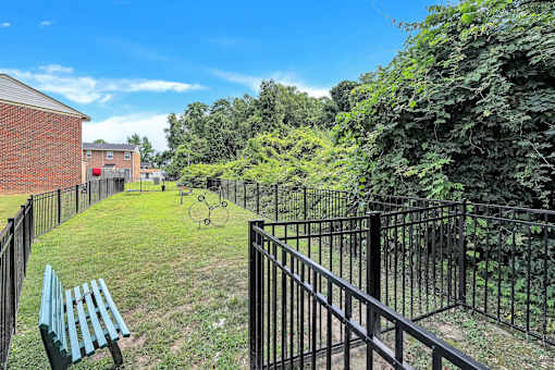 A black metal fence surrounds a green park area.