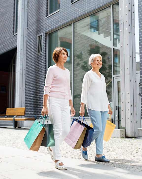 Two women walking down the street carrying shopping bags.