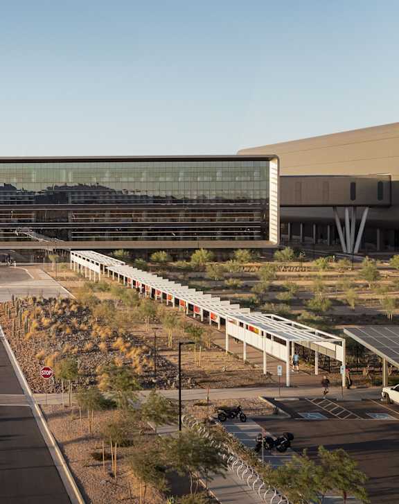 A large building with a long glass facade is surrounded by a parking lot.