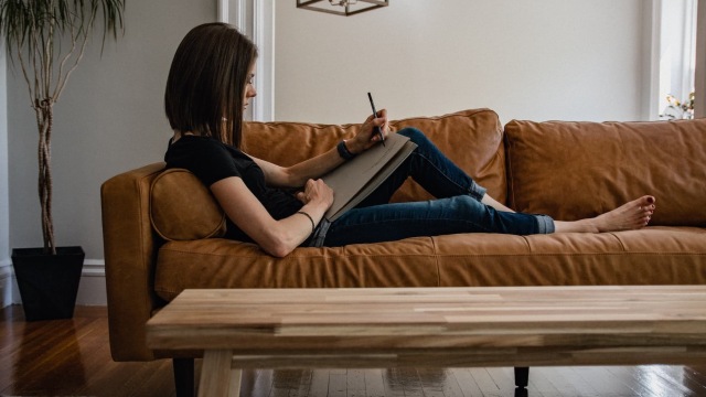 lifestyle image of a woman laying on the couch and working