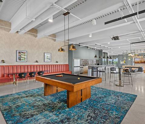 A room with a pool table and a bar area.