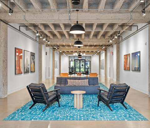 A room with a blue rug and chairs.