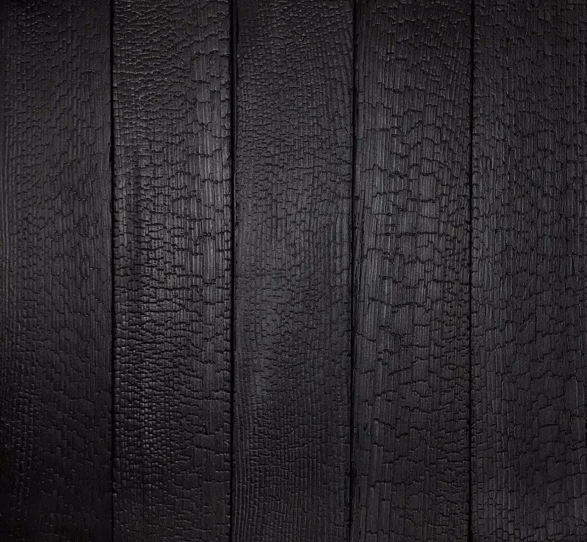 Close-up of vertically arranged charred wooden planks with cracked textures.