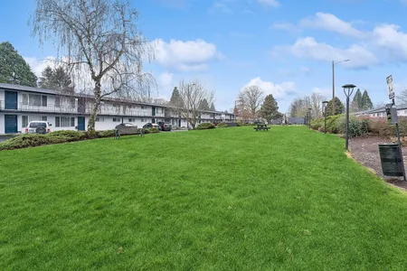 Charming residential complex with lush green lawns, a serene setting, and ample outdoor seating.