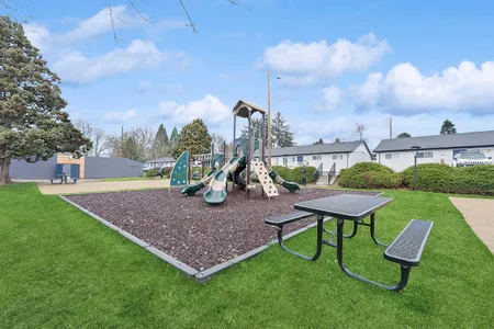 Charming outdoor playground with slides and climbing features surrounded by lush greenery, perfect for family enjoyment and outdoor activities.