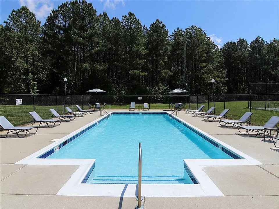 Inviting outdoor pool area surrounded by lush greenery with multiple sun loungers.