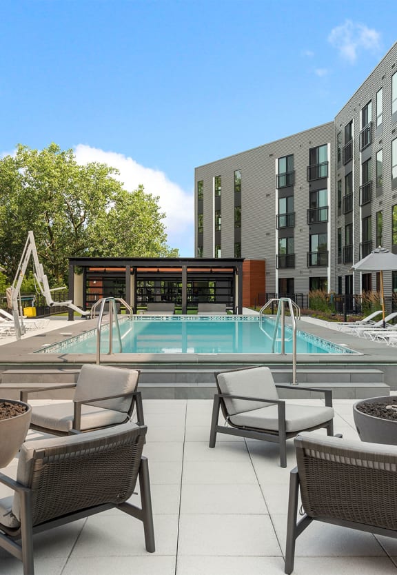 a pool with lounge chairs and fire pits in front of a building