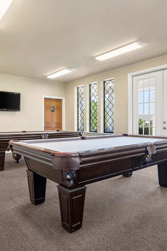 A room with a pool table and a television mounted on the wall.
