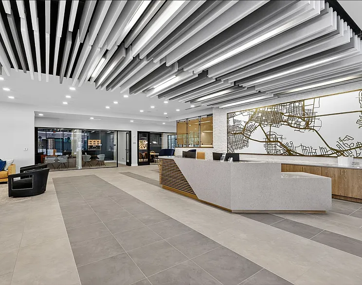 Modern apartment lobby with stylish ceiling design, inviting seating area, and a sleek reception desk beneath a large map artwork.