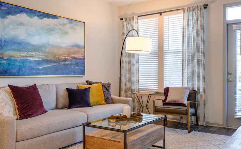 Cozy, clean living room with wooden accent furniture and large windows