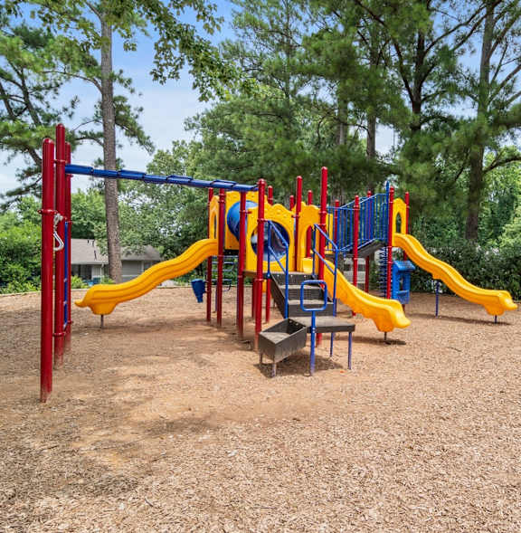 A playground with a red and yellow slide and a blue and red climbing frame.