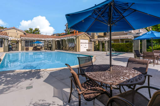 our resort style swimming pool is surrounded by patio furniture and umbrellas