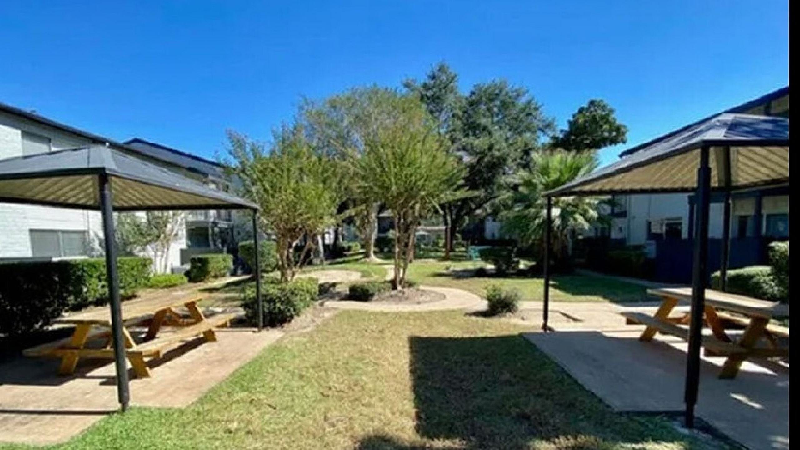Charming apartment community courtyard with lush greenery, shaded picnic areas, and a peaceful ambiance.