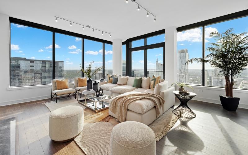a living room with a couch, chairs and large windows