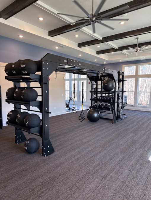 A home gym with a weight rack and a ceiling fan.