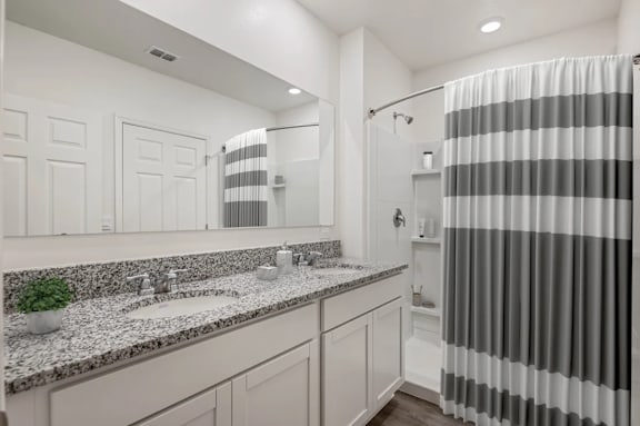 A bathroom with a striped shower curtain and a marble countertop.