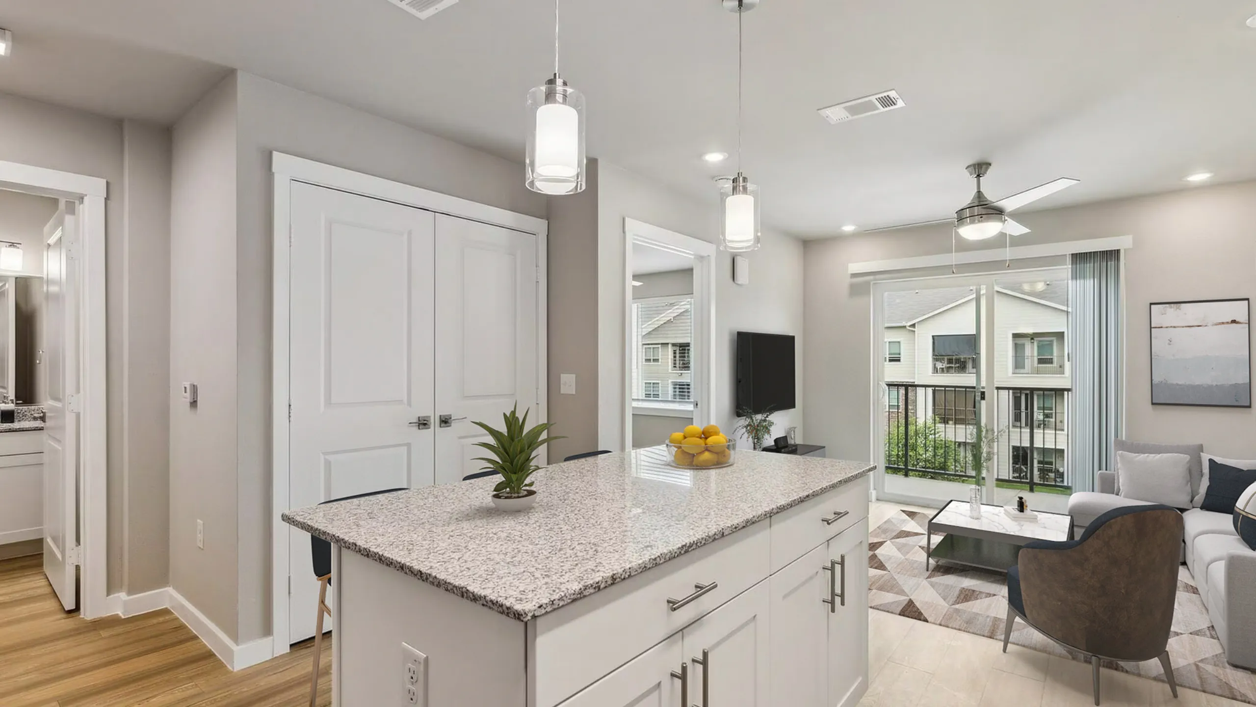 Chic apartment interior showcasing a modern kitchen island with granite countertops, a cozy living room, and abundant natural light from large windows overlooking a serene view.