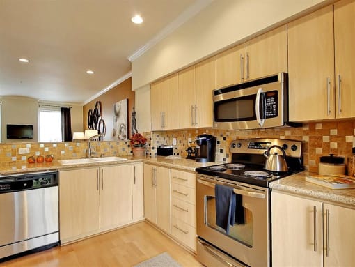 Kenmore WA Apartments for Rent - Northshore Townhomes - Modern Kitchen with Stainless Steel Appliances, Granite Countertops, Tan Tile Backsplash, Wood-Style Cabinetry, and L-Shape