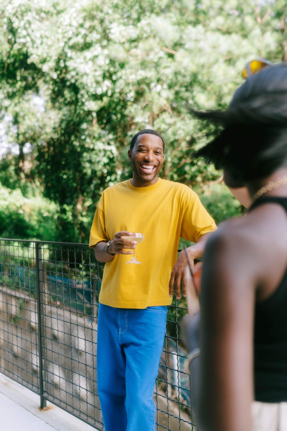Smiling person holding a drink & chatting with a friend