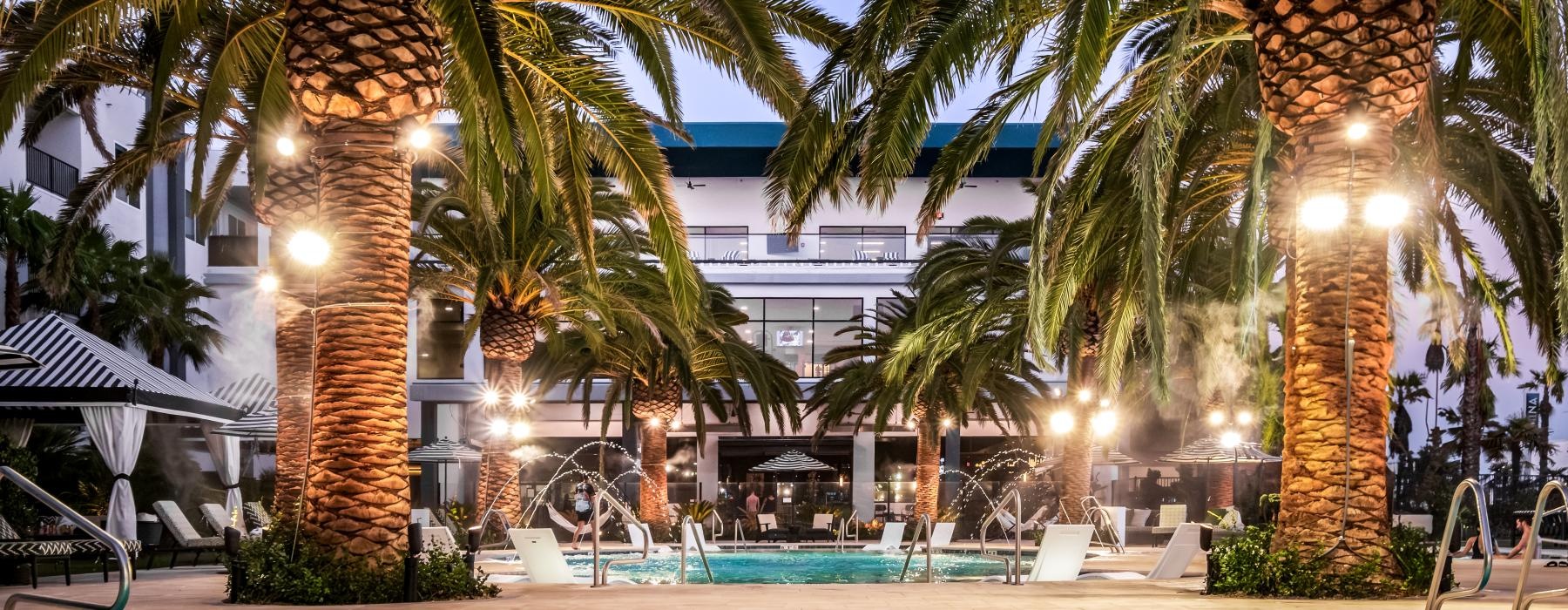 A pool with palm trees at Ilumina at Raider's Way apartments near Las Vegas