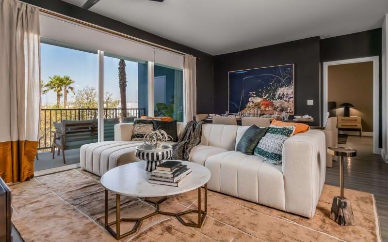 Living room with a large window and balcony at Ilumina at Raider's Way luxury apartments in Henderson, NV