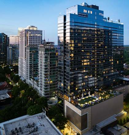 A tall building with a blue sign on the top stands out among other buildings at 903 Peachtree in Atlanta, 30309