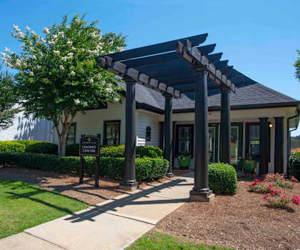 A building with a covered walkway entrance surrounded by greenery at The Madison Apartments and Townhomes, Georgia 30044