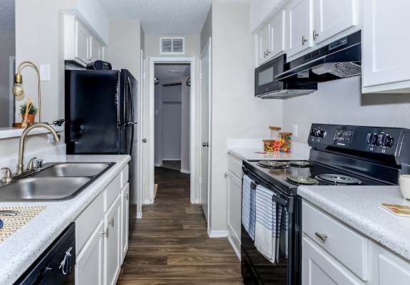 a kitchen with black appliances and white cabinets at The Davis Apartments, Huntsville, 35816