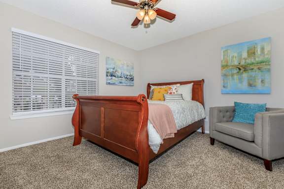 A bedroom with a bed, a couch, and a ceiling fan.at The Davis Apartments, Huntsville, AL 35816