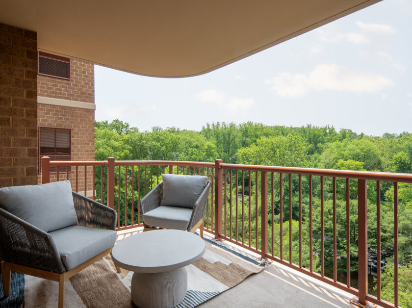 A large balcony with seating and tree views.
