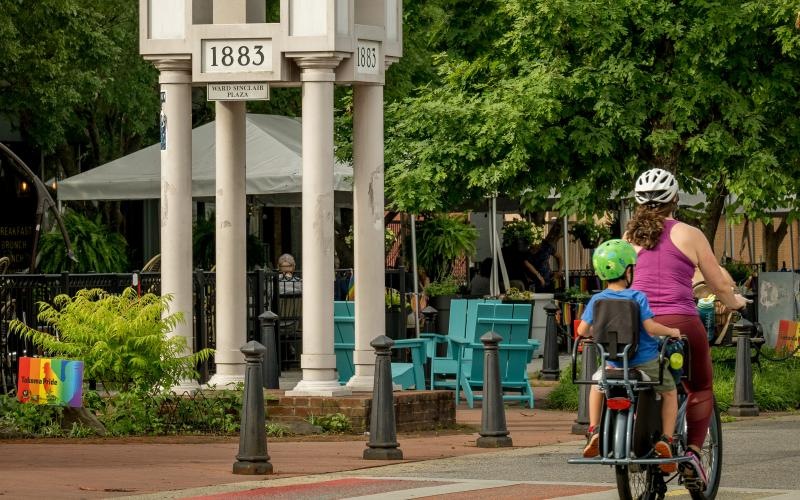 a couple of people ride bikes under a clock tower