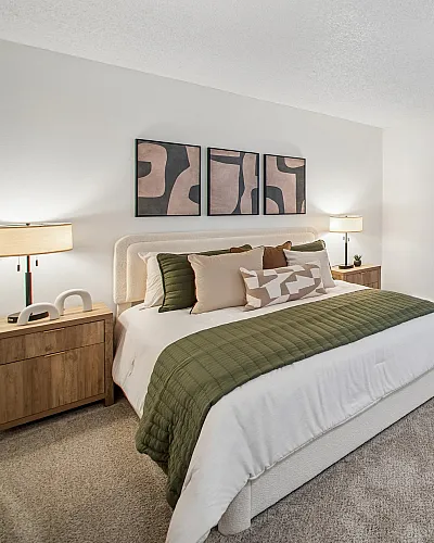 Inviting modern bedroom featuring a luxurious bed with stylish cushions, chic artwork, and elegant lighting, creating a serene ambiance.