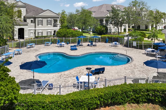 Resort-style swimming pool with lounge chairs and tables.