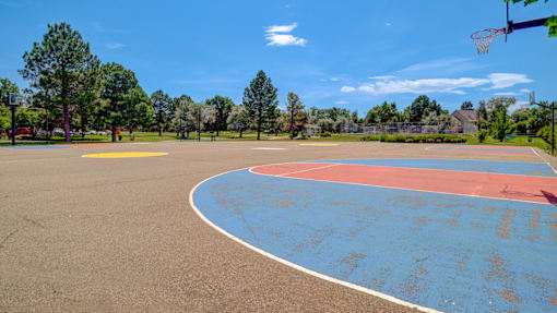 A basketball court with a blue and red surface and a basketball hoop.