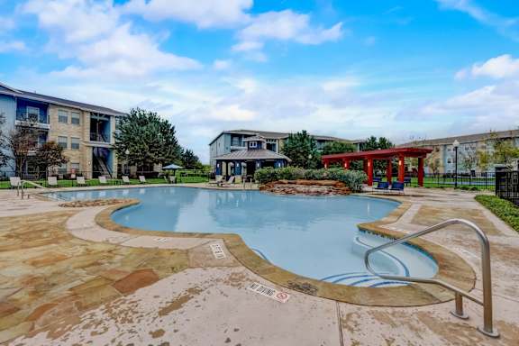 A large outdoor swimming pool with a red bench and a metal railing.