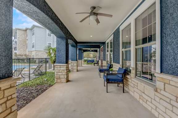 A long covered walkway with chairs and a ceiling fan.