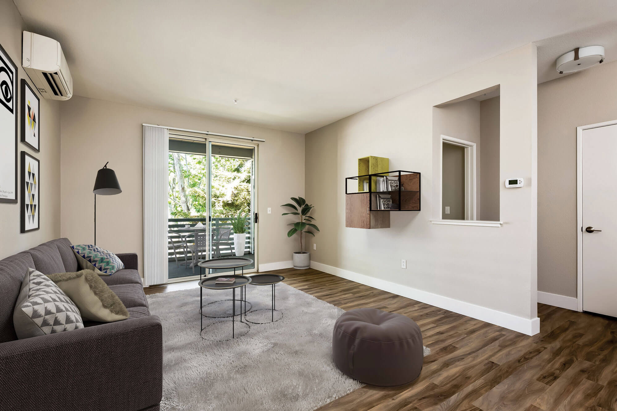 Living room at Bell Almaden in San Jose, CA with large glass sliding door out to balcony patio, with mounted air conditioning unit on the wall and several decorative items