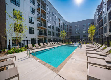 an outdoor pool with lounge chairs and an apartment building